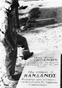 Γερμανός στρατιώτης επάνω σε αναμνηστική επιγραφή για την καταστροφή του χωριού Κάνδανος στην Κρήτη, που έγινε σε αντίποινα για την αντίσταση των πολιτών του στην Μάχη της Κρήτης.